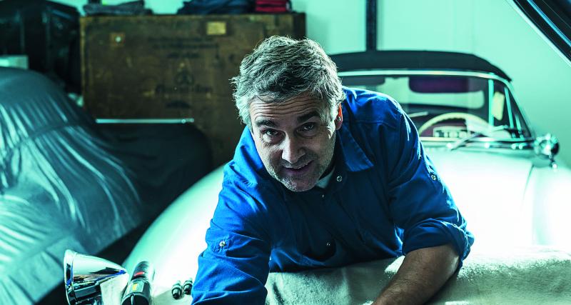 Nicolas Jambon Bruguier dans la cour de son atelier, assis dans la 300 SL ex-Moss.